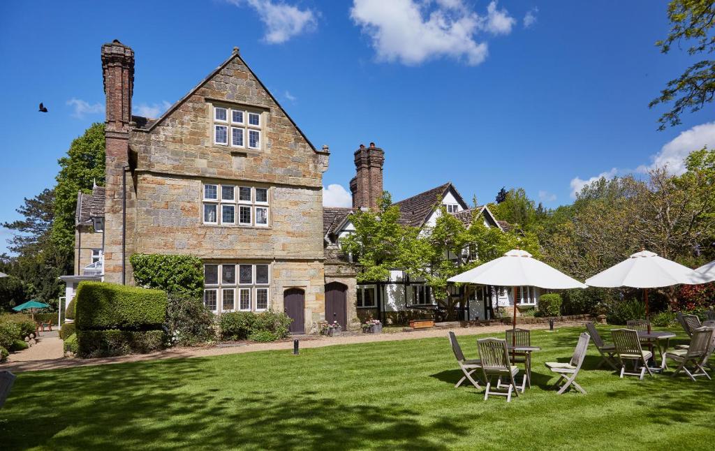 een huis met ligstoelen en parasols ervoor bij Ockenden Manor Hotel & Spa in Cuckfield