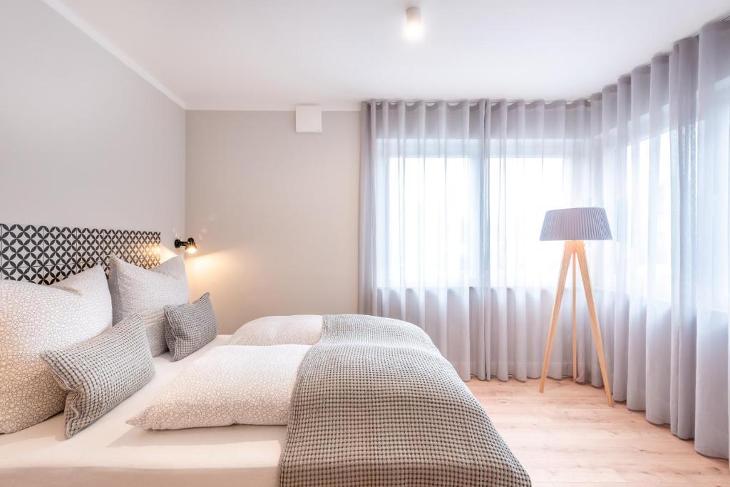 een witte slaapkamer met een bed en een raam bij The Woodmans Airport Boardinghouse in Düsseldorf