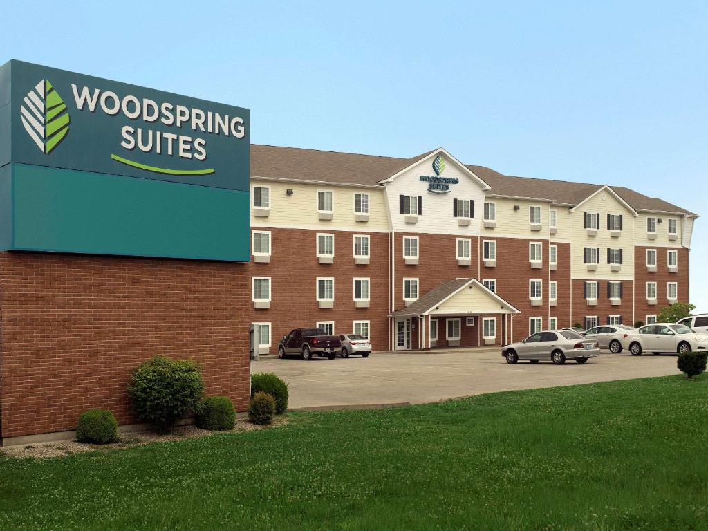 een bord voor een gebouw met auto's op een parkeerplaats bij WoodSpring Suites Louisville Clarksville in Clarksville