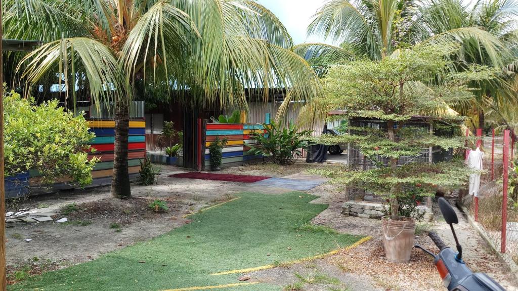 un jardin avec une clôture et une cour avec des palmiers dans l'établissement Tony’s Guesthouse at Teluk Bahang, à Batu Ferringhi