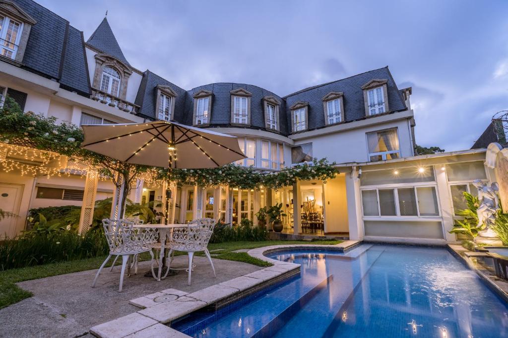 un domaine avec une piscine et une table avec un parasol dans l'établissement Hotel San Carlos, à Guatemala