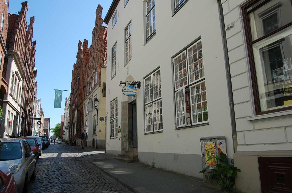 Jugendherberge Lübeck Altstadt في لوبيك: شارع فيه مباني وسيارات تقف في شارع مرصوف بالحصى