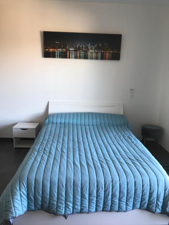 - un lit avec une couette bleue dans une chambre dans l'établissement charmant studio dans résidence neuve et calme, à Corte