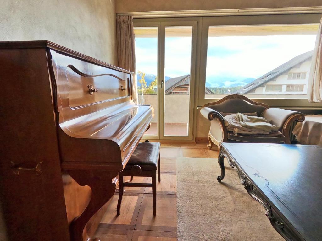 a living room with a piano and a couch at Beautiful apartment over the mountain in Crans-Montana