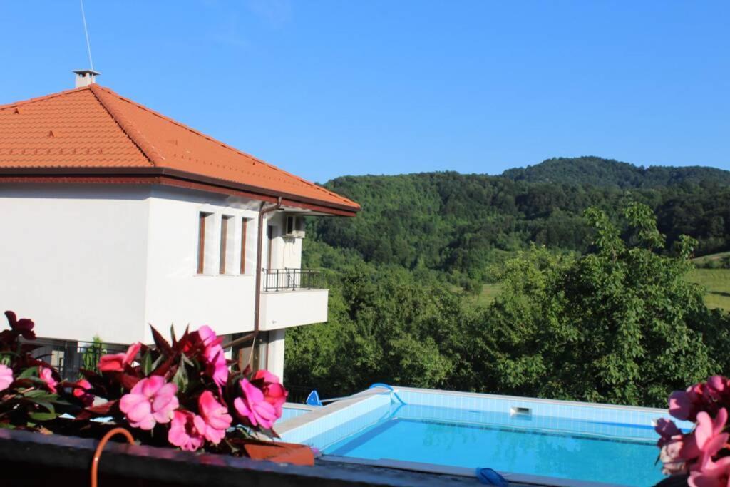 Blick auf ein Gebäude mit einem Pool und Blumen in der Unterkunft Бадевски рай- къща София in Weliko Tarnowo