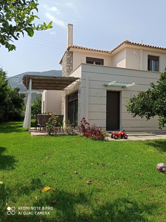 une maison avec une pelouse devant elle dans l'établissement Aloe Apartment in Epidaurus, à Ancient Epidavros