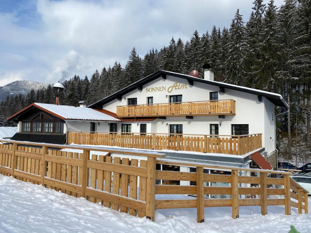 a building with a wooden fence in the snow at Hotel Sonnenalm Stuhleck in Spital am Semmering