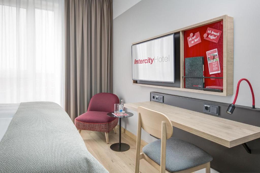 Cette chambre comprend un lit, un bureau et une télévision. dans l'établissement IntercityHotel Wiesbaden, à Wiesbaden