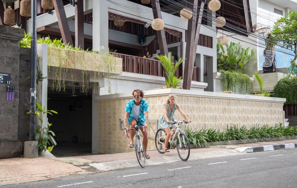 zwei Leute, die mit ihren Fahrrädern eine Straße hinunterfahren in der Unterkunft Kayangan Boutique Hotel in Sanur