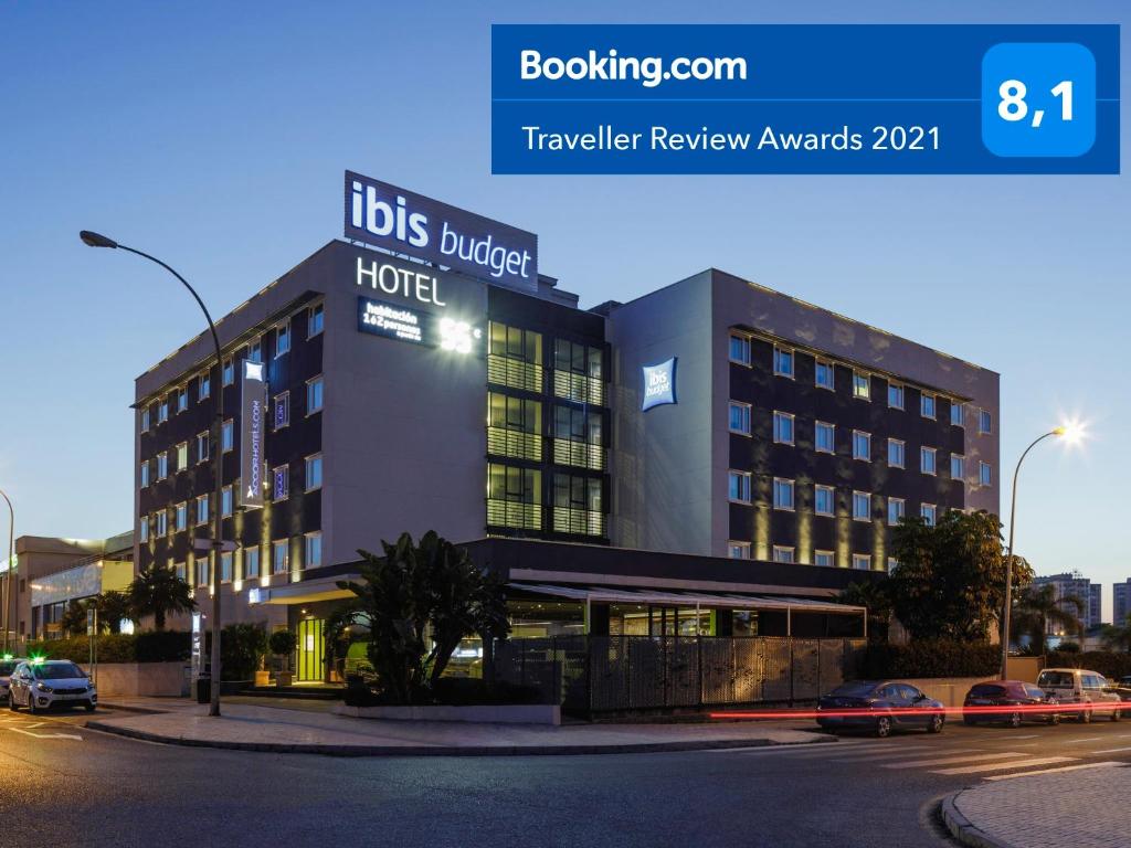 hotel na ulicy z samochodami zaparkowanymi przed nim w obiekcie Ibis Budget Málaga Aeropuerto Avenida de Velazquez w Maladze