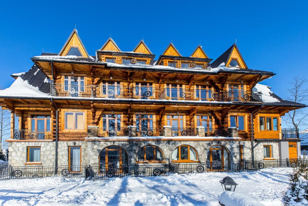 ein großes Holzhaus im Schnee in der Unterkunft Apartamenty na Leśnej in Bukowina Tatrzańska