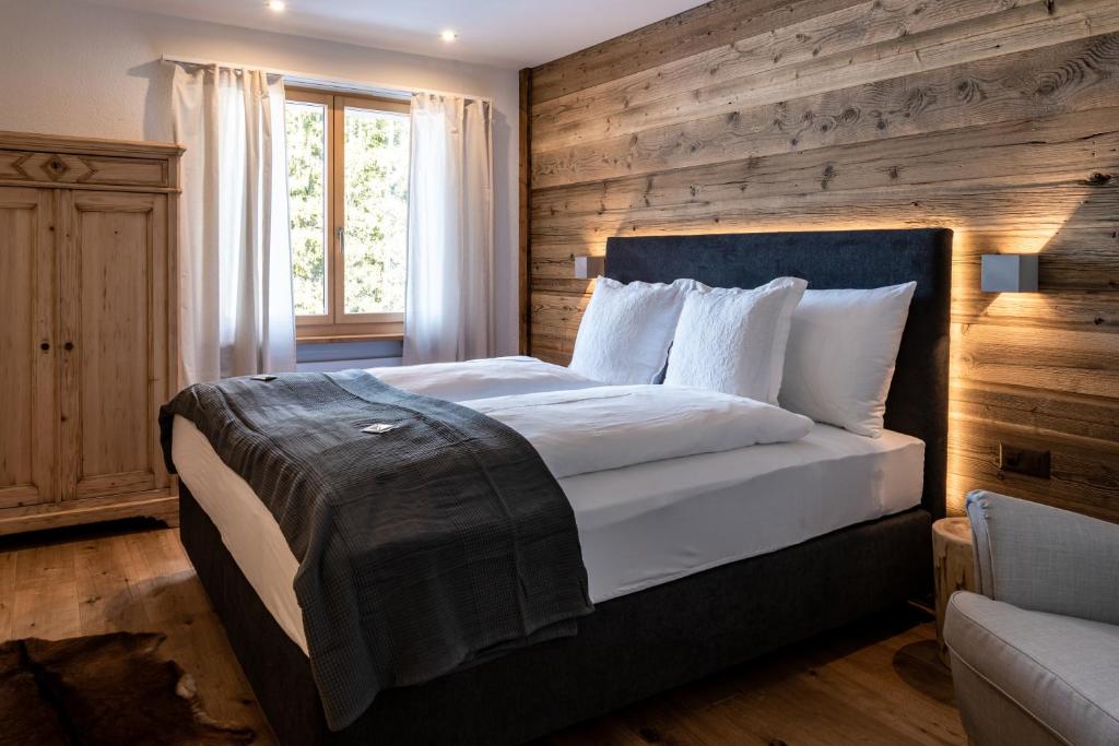 ein Schlafzimmer mit einem großen Bett und einer Holzwand in der Unterkunft Typically Swiss Hotel Ermitage in Kandersteg