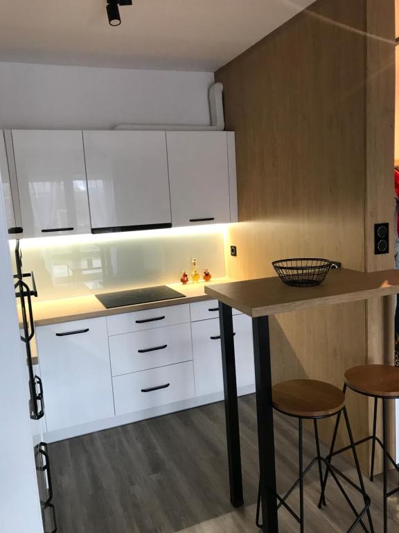 uma cozinha com armários brancos, uma mesa e bancos em Apartament na Skrzypka em Cieszyn