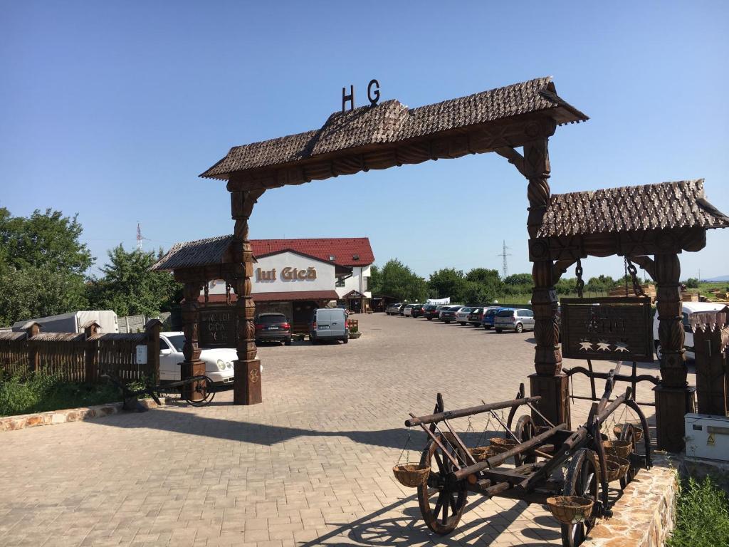 a wooden archway with a cart in a parking lot at Hanu lui Gica Spa in Satu Mare