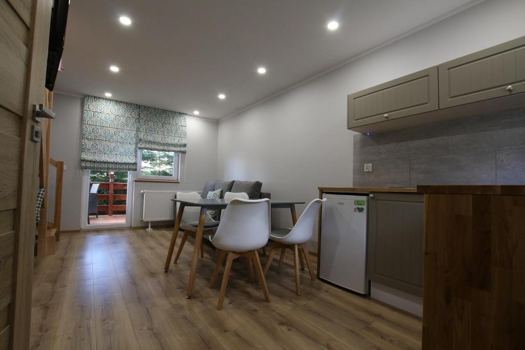 a kitchen with a table and white chairs in a room at Auto-Camping Park in Jelenia Góra