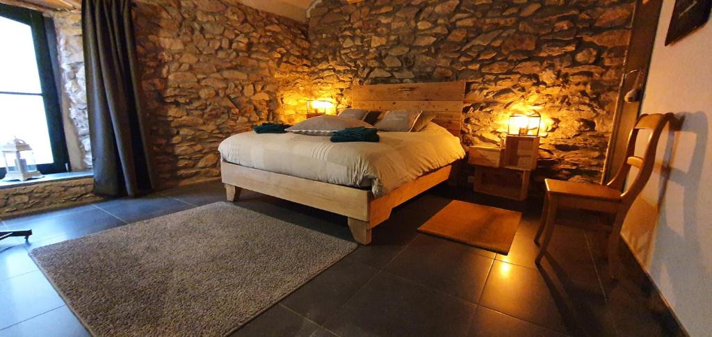 una camera con letto e parete in pietra di O Près de la Lienne, maison de campagne de charme, accord parfait entre confort et authenticité a Lierneux