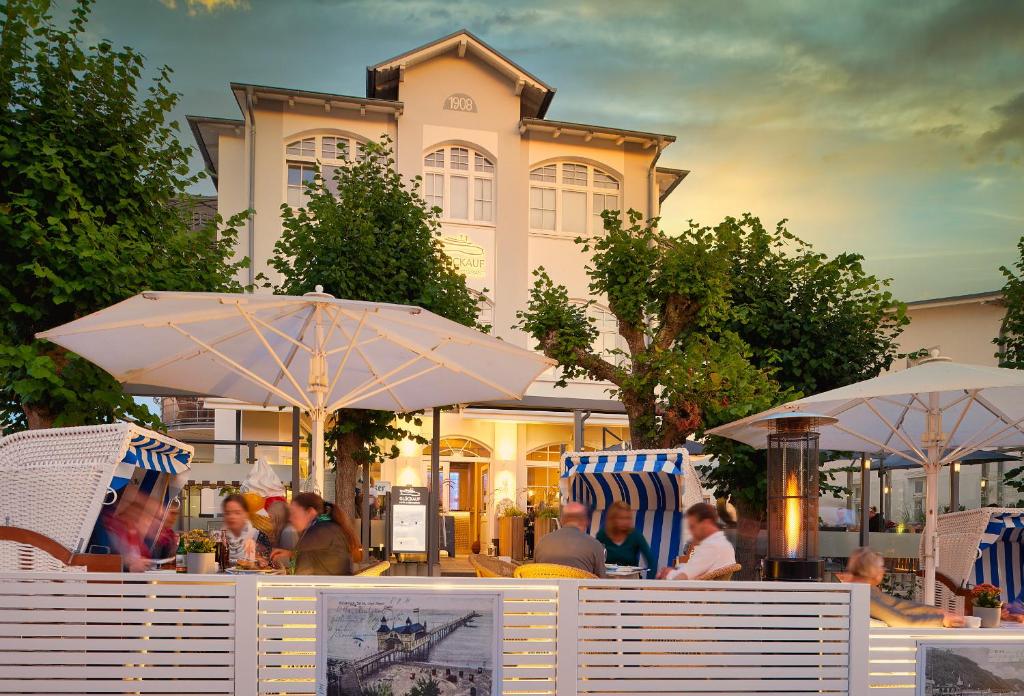 eine Gruppe von Menschen, die an einem Tisch mit Sonnenschirmen sitzen in der Unterkunft Hotel Glückauf 1908 in Ostseebad Sellin