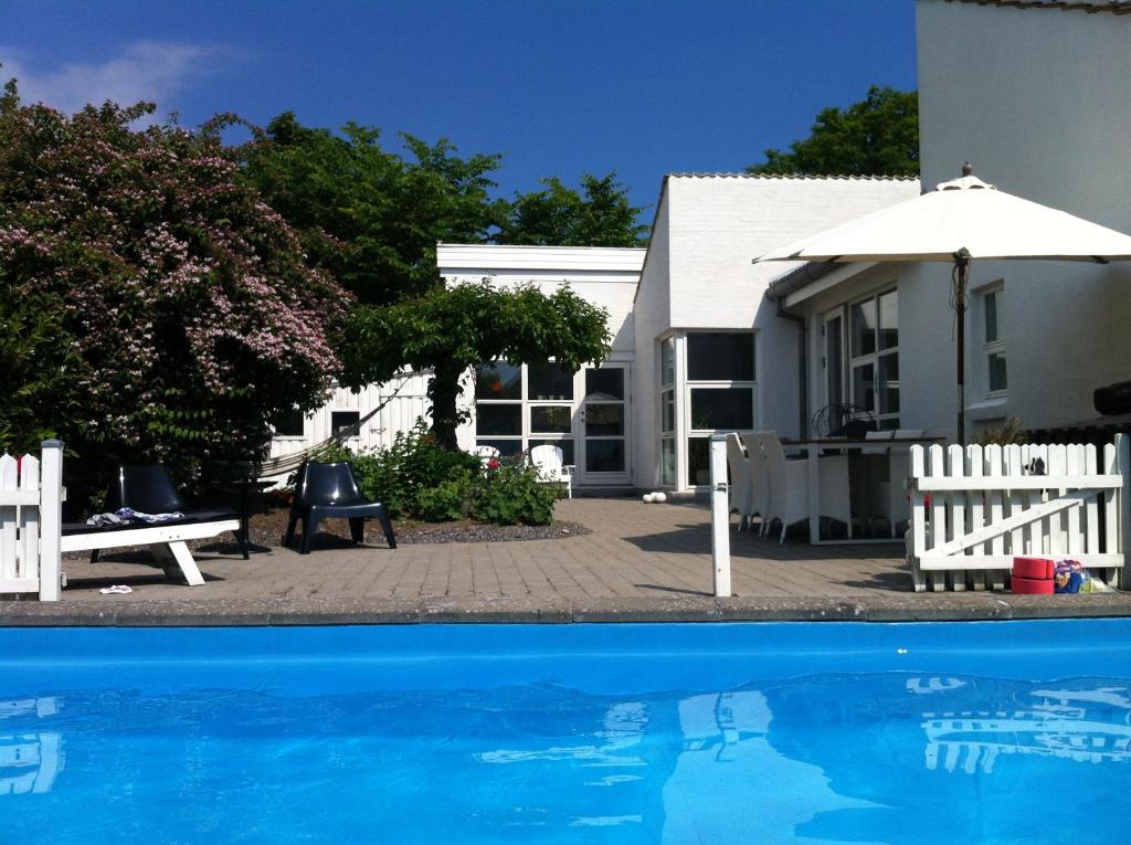 una casa e una piscina con ombrellone di Kathrines Bed & Breakfast a Svendborg