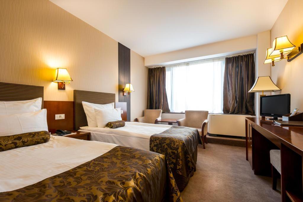 a hotel room with two beds and a television at Grand Hotel Napoca in Cluj-Napoca