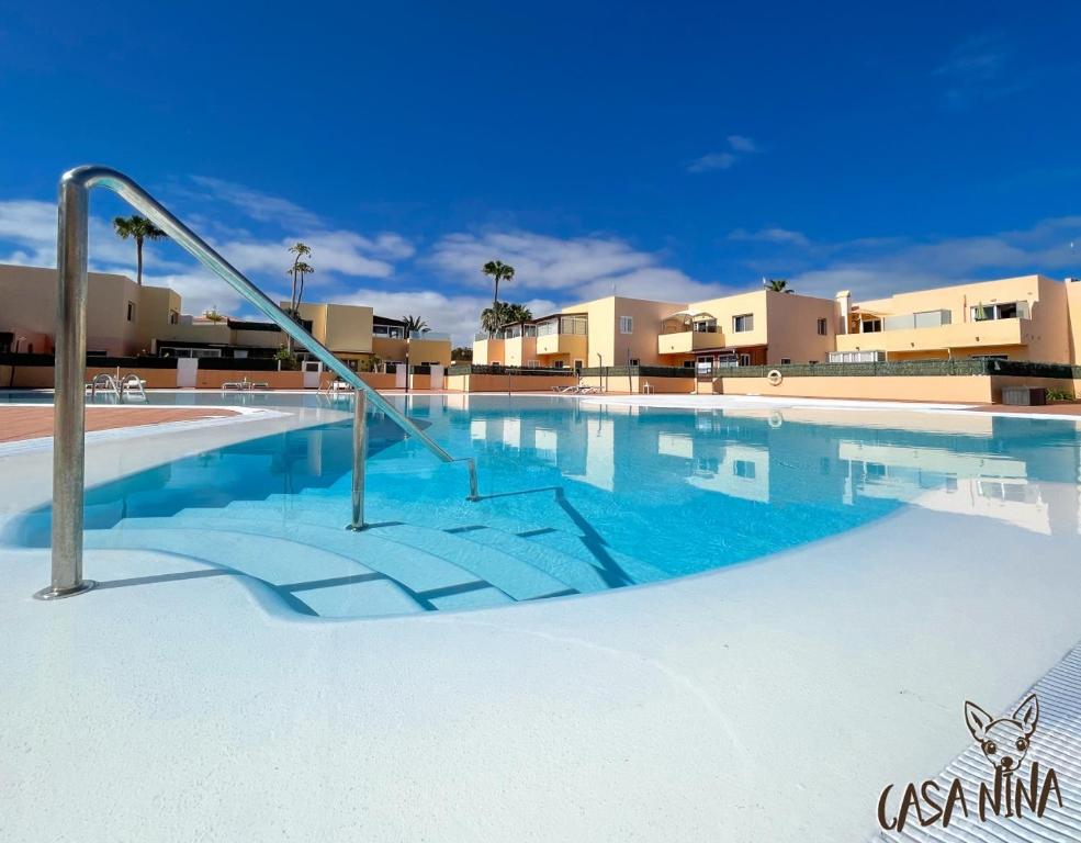 a large swimming pool with a metal handrail in the middle at B-Rent Los Delfines Casa Nina in Corralejo