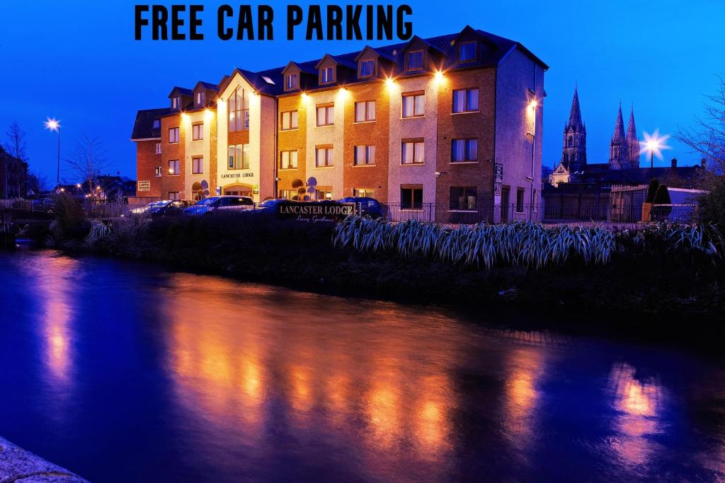 een gebouw naast een rivier 's nachts met de woorden gratis parkeren bij Lancaster Lodge in Cork