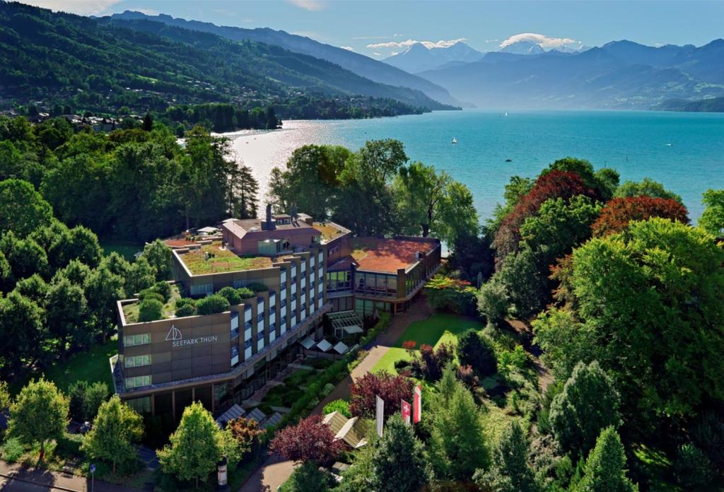 z góry widok na budynek obok jeziora w obiekcie Hotel Seepark Thun w mieście Thun