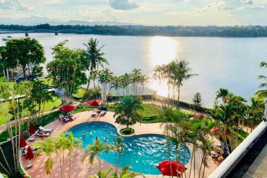 vistas a una piscina junto a un cuerpo de agua en Century Riverside Hotel Hue, en Hue