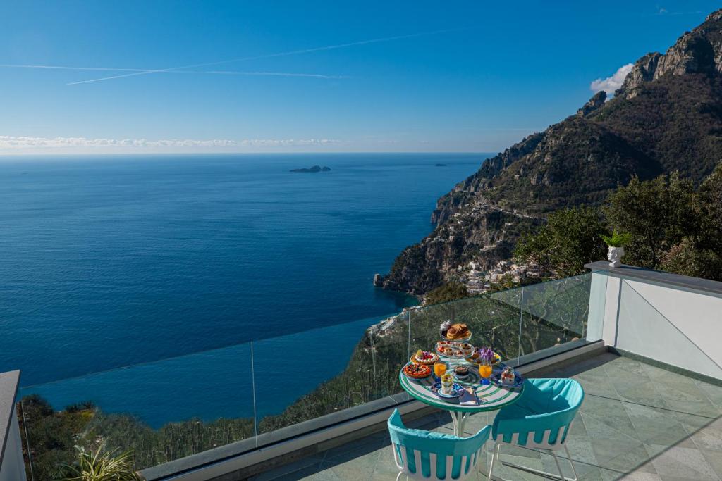 un tavolo e sedie su un balcone con vista sull'oceano di Petrea Lifestyle Suites a Positano