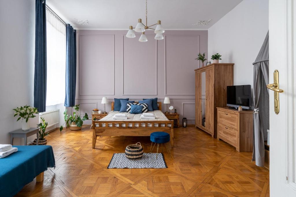 a bedroom with a bed with blue pillows and a tv at Sleeping in Krakow Main Market in Kraków