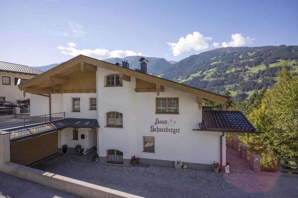 ein weißes Gebäude mit einem Dach mit Bergen im Hintergrund in der Unterkunft Apartment Zell am Ziller 2 in Zell am Ziller