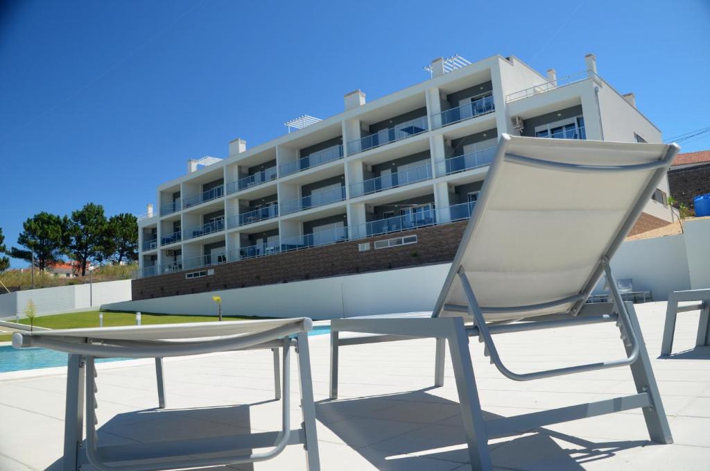 a chair and table in front of a hotel at Cazenn Nazaré - Apartment Z in Nazaré