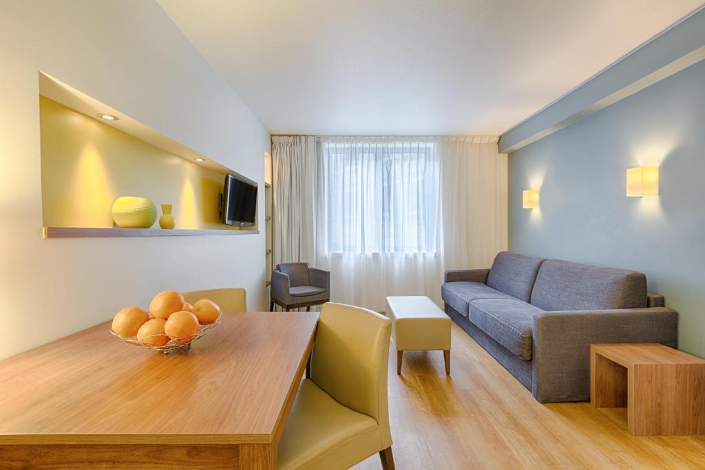 uma sala de estar com uma mesa e um sofá em Citadines Place d'Italie Paris em Paris