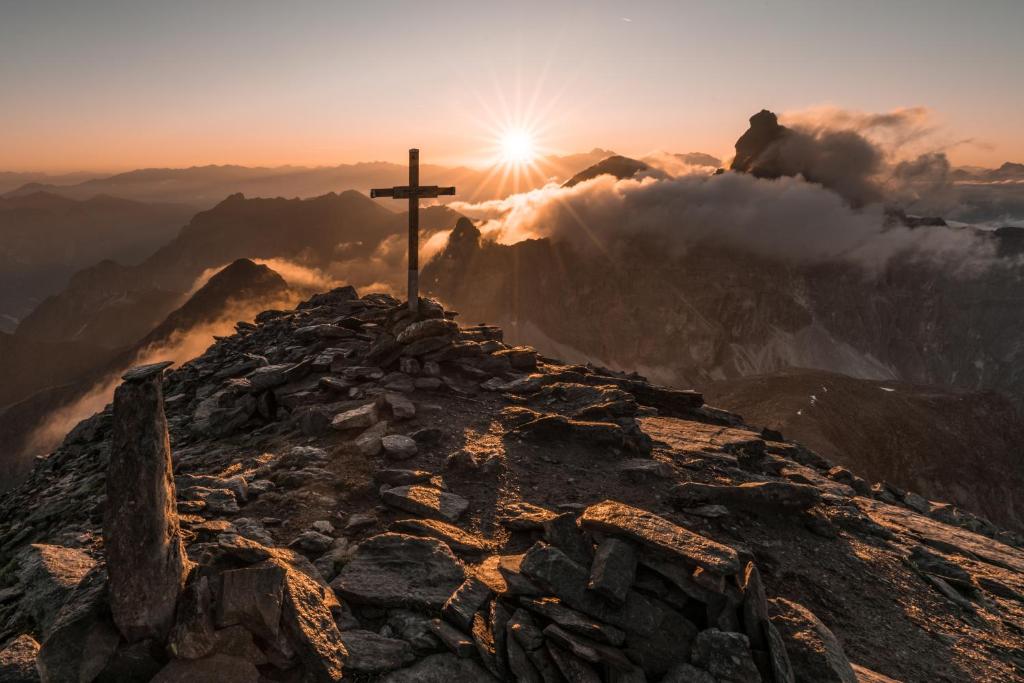 una croce sulla cima di una montagna al tramonto di Apartments Ban Guggugg a Colle Isarco