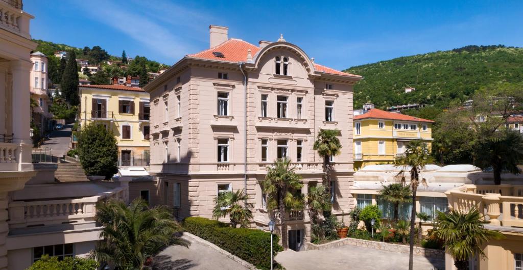 un grand bâtiment avec des palmiers devant lui dans l'établissement Villa Abbazia - Liburnia, à Opatija