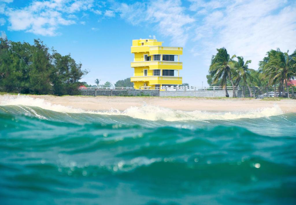 ein gelbes Gebäude am Strand neben dem Meer in der Unterkunft Pranaav Beach Resort in Puducherry