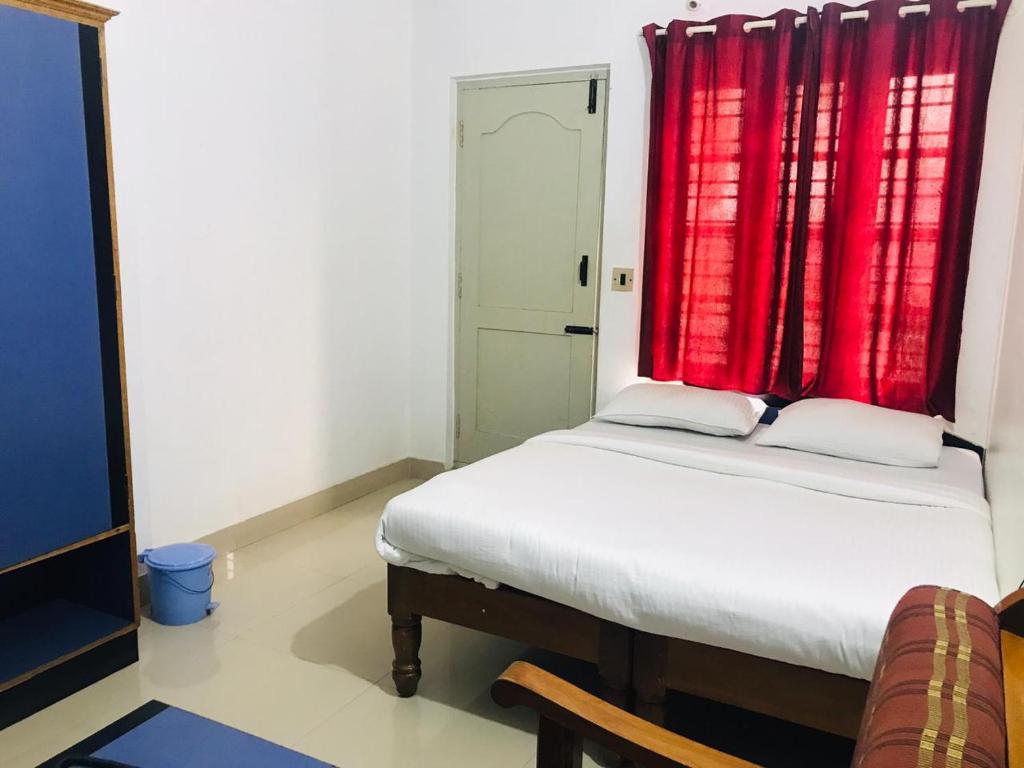 a bedroom with a bed with a red curtain at Ice Berg Deluxe Lodge in Kushālnagar