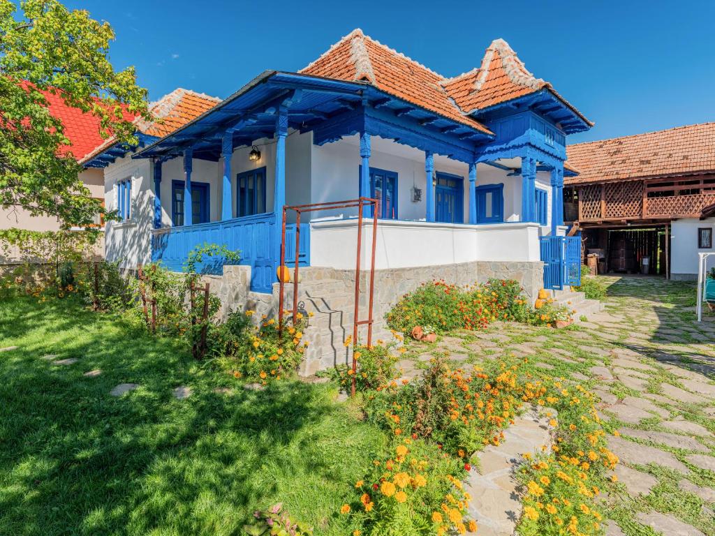 a blue and white house with flowers in the yard at Casa de vacanta traditionala romaneasca in Schiuleşti