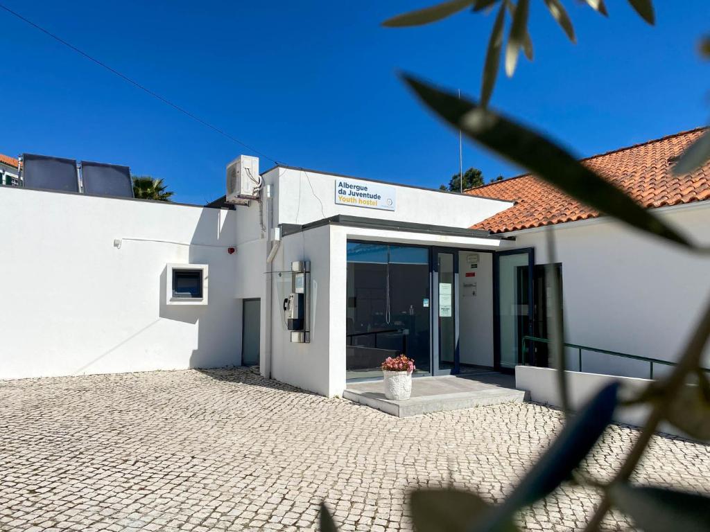 un edificio bianco con una porta con un vaso di fiori di Albergue da Juventude a Tancos