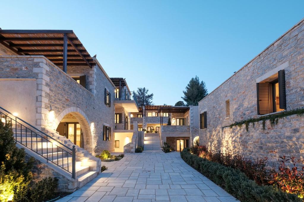 a courtyard of a house with a stone wall at Margo Beach Hotel in Gythio