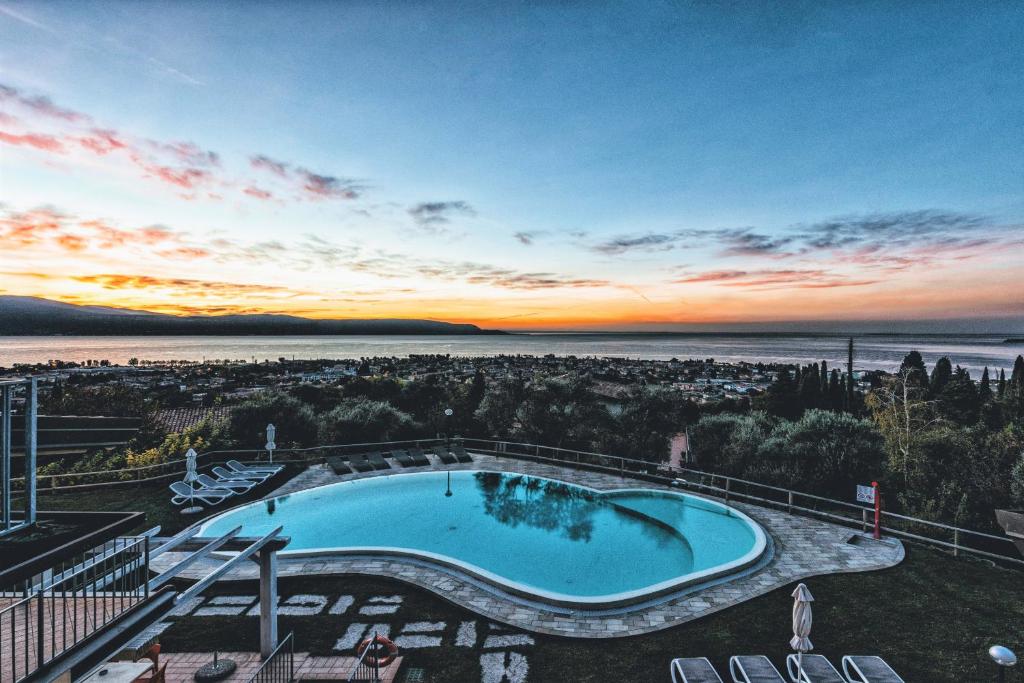 - une piscine au-dessus d'un bâtiment avec un coucher de soleil dans l'établissement La Chioma di Berenice Garda Residence, à Toscolano Maderno