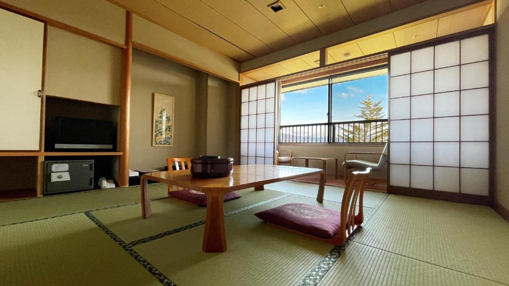 een woonkamer met een tafel en een raam bij Miyajima Morinoyado in Miyajima