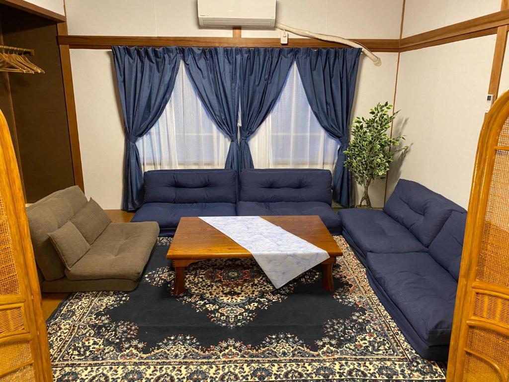 een woonkamer met een blauwe bank en een tafel bij Ise Toyohama Villa - Vacation STAY 11133 in Ise