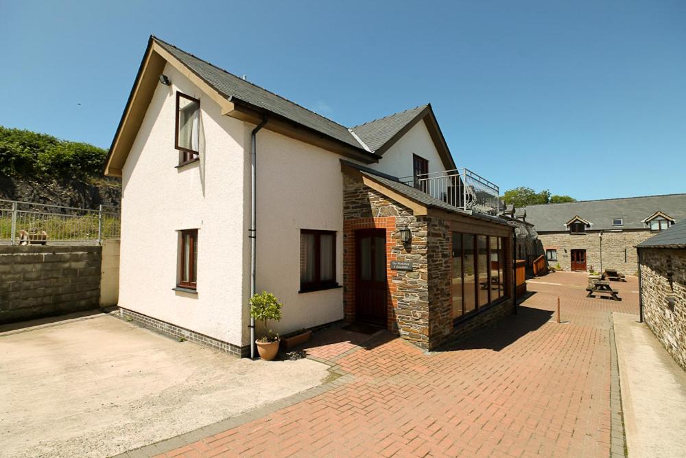 una casa bianca con un marciapiede di mattoni accanto a un edificio di The Workshop ad Aberystwyth