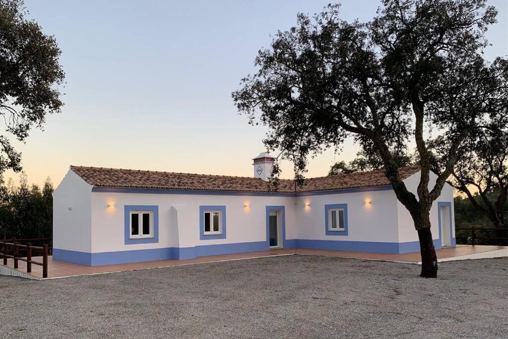 uma casa branca com uma árvore em frente em Monte da Rocha em Santiago do Cacém