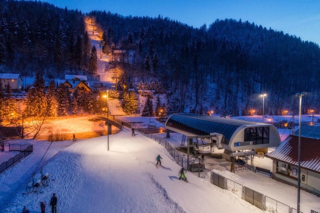 eine Ski-Lodge mit Leuten, die nachts im Schnee Ski fahren in der Unterkunft Willa Pod Kolejką in Szczawnica