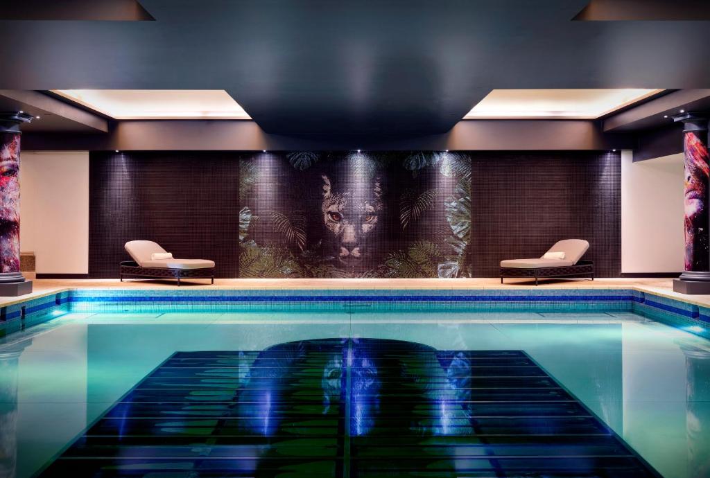 uma piscina num quarto de hotel com duas cadeiras em NYX Hotel London Holborn by Leonardo Hotels em Londres