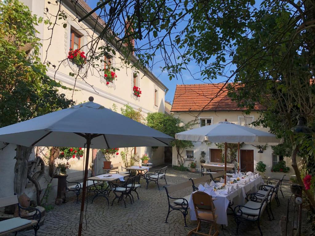 an outdoor patio with tables and chairs and umbrellas at CALLM aka Zum goldenen Löwen - zu Nacht bei der Destillerie in Kallmünz