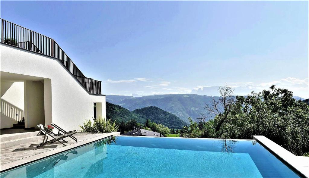 una piscina frente a una casa con montañas en Hotel & Gasthof zum Hirschen, en San Genesio Atesino