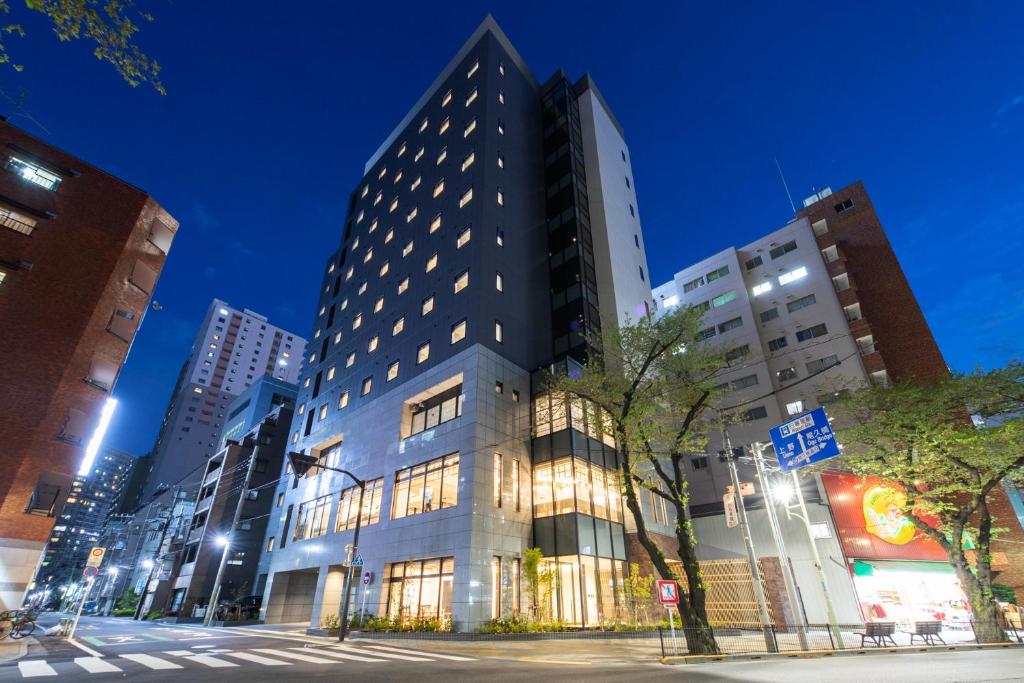 un grand bâtiment sur une rue de la ville la nuit dans l'établissement Almont Hotel Nippori, à Tokyo