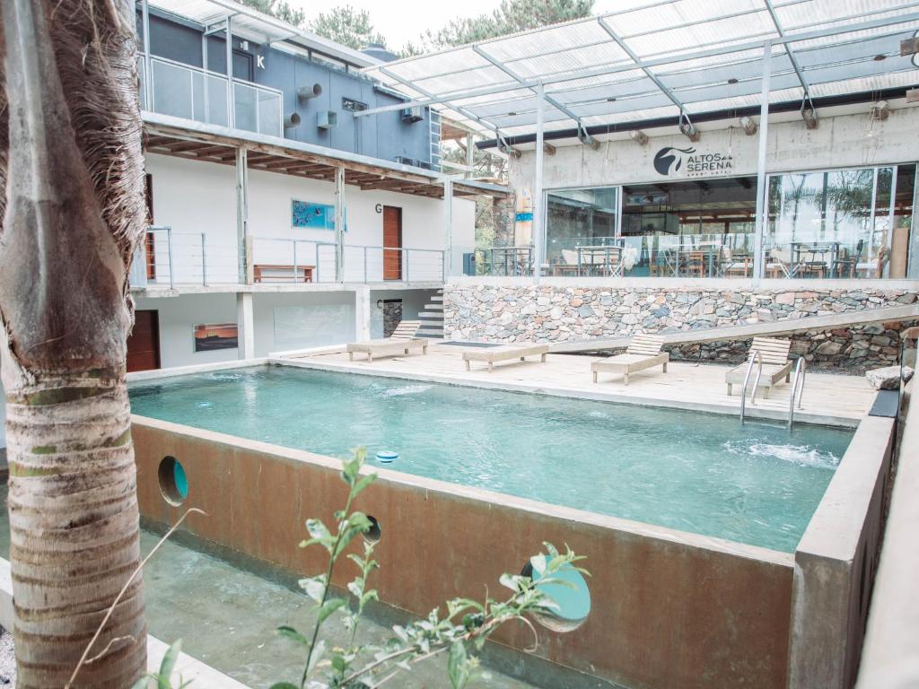 una piscina con una palma di fronte a un edificio di Altos de la Serena Apart Hotel a La Paloma